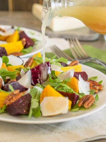 Pouring dressing onto a beet and arugula salad