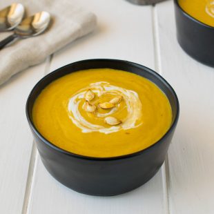 Roasted pumpkin and root vegetable soup garnished with pumpkin seeds and sour cream.