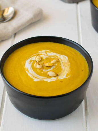 Roasted pumpkin and root vegetable soup garnished with pumpkin seeds and sour cream.