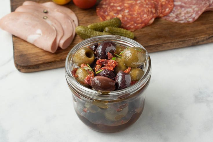 A jar full of olives, sun-dried tomato and rosemary