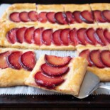 A square slice of plum tart on a spatula