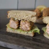 A closeup of a salmon fish finger/fish stick sandwich cut so you can see the inside of the salmon