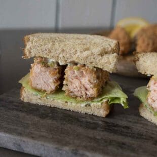 A closeup of a salmon fish finger/fish stick sandwich cut so you can see the inside of the salmon