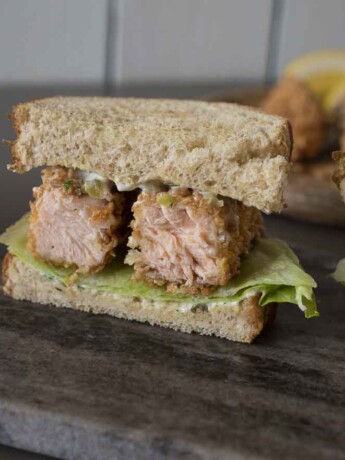 A closeup of a salmon fish finger/fish stick sandwich cut so you can see the inside of the salmon