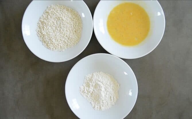 3 white bowls with panko breadcrumbs, beaten egg and flour