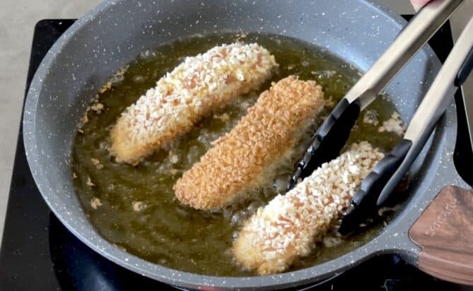Shallow frying salmon fish fingers/fish sticks in oil in a frying pan