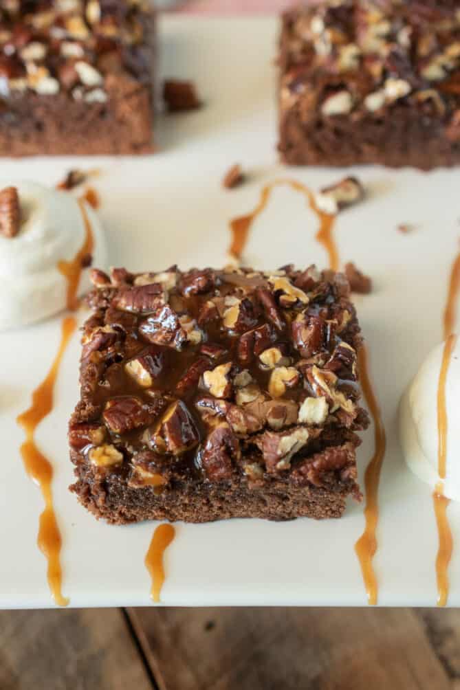A piece of brownie topped with pecans and caramel sauce