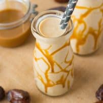 A milk bottle filled with salted caramel date shake with caramel drizzled on glass