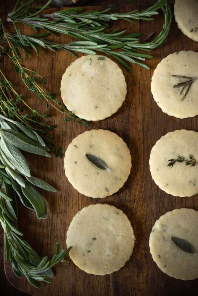 Rows of shortbread crackers viewed from overhead with fresh rosemary, sage and thyme.