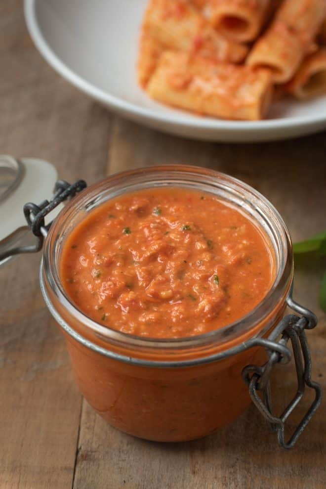 Sicilian tomato pesto sauce in a jar with a plate of pasta
