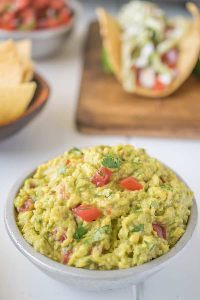 Signature guacamole served in a silver bowl with fish tacos