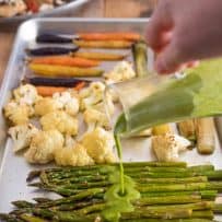 Pouring herb sauce over roasted asparagus