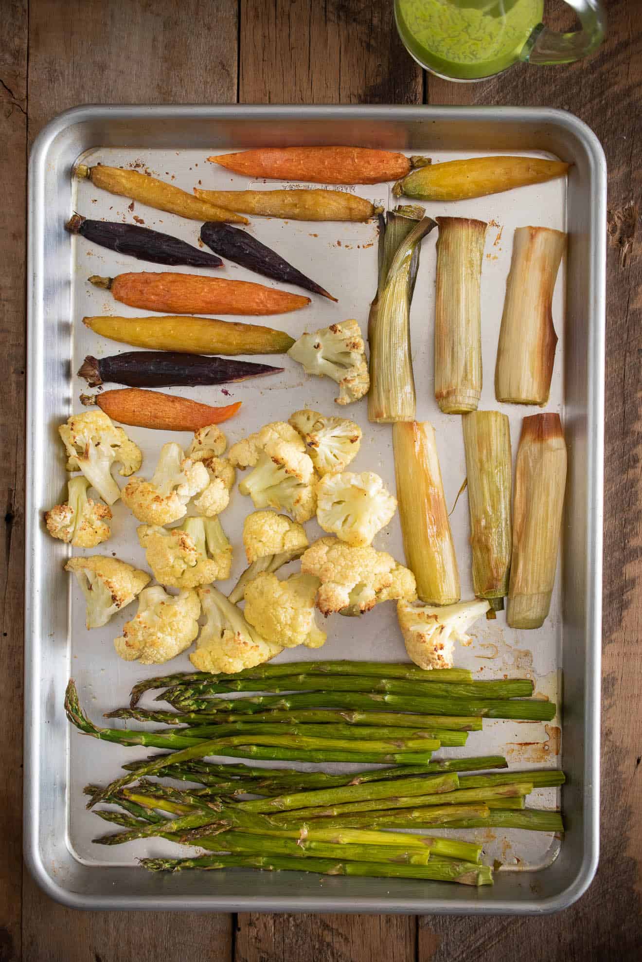 Asparagus, cauliflower, leeks and colorful carrots on a sheet pan freshly roasted