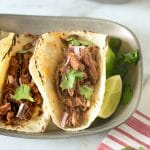 Slow cooker barbacoa tacos. Beef roast is slowly cooked in a homemade guajillo chile pepper sauce until it is fall apart and shredded, served simply in soft tortillas with red onion and cilantro.