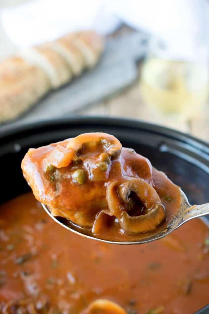 A ladle of chicken with tomato sauce mushrooms and capers