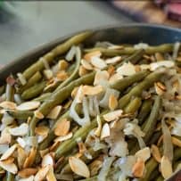 Green beans with shallots and sliced almonds served in an oval bowl