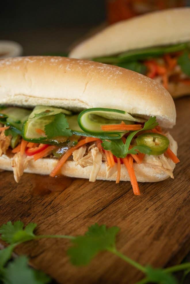 A closeup showing the banh mi filling of shredded chicken, shaved cucumber, carrot slaw and cilantro