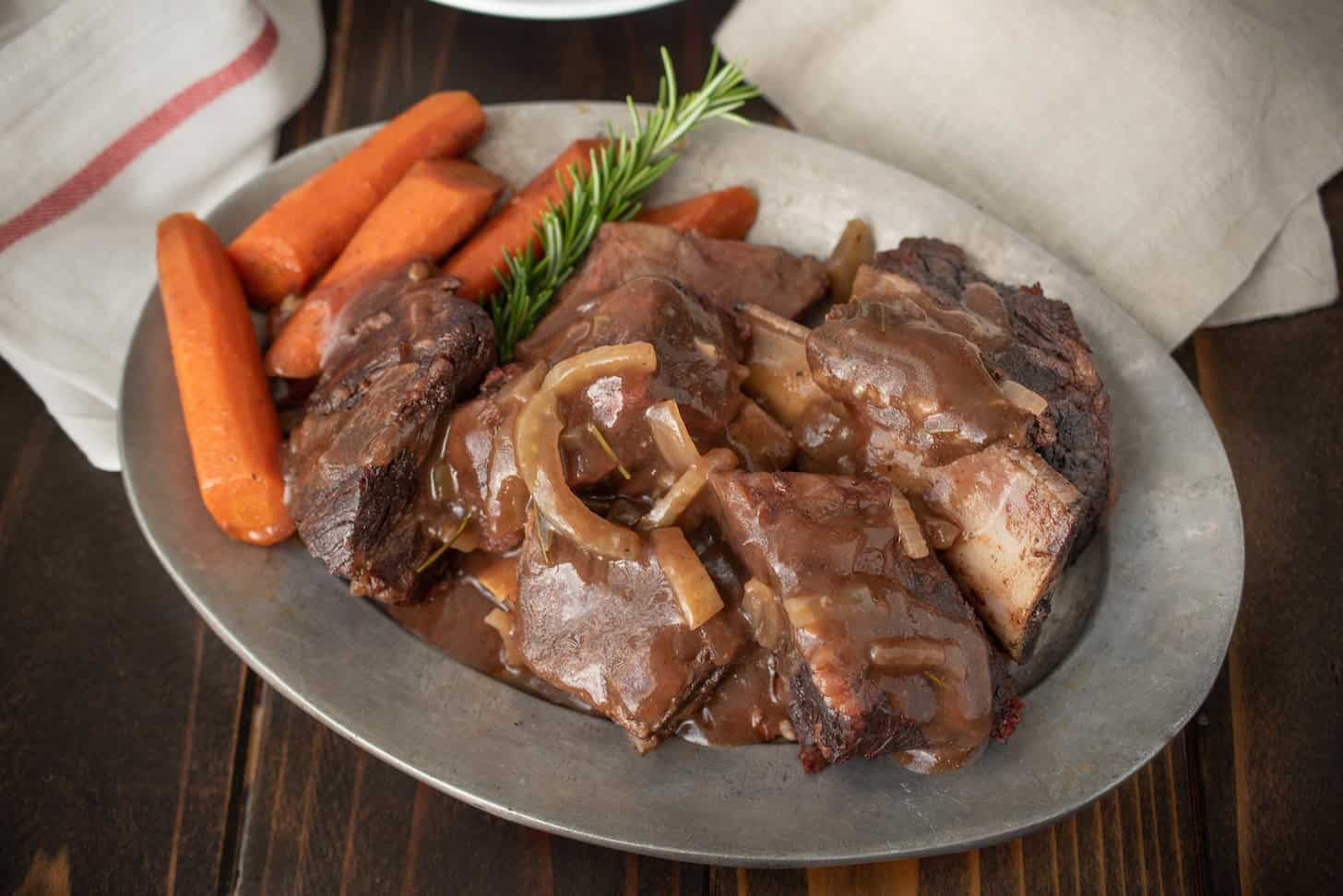 A platter of slow cooked short ribs with carrots