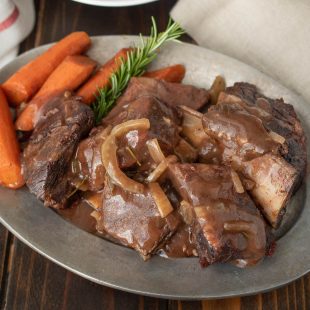 An oval platter of Tuscan short ribs with carrots