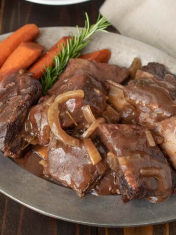 An oval platter of Tuscan short ribs with carrots