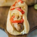 Slow cooker beer bratwurst on a bun with onions and peppers
