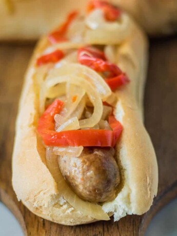Slow cooker beer bratwurst on a bun with onions and peppers