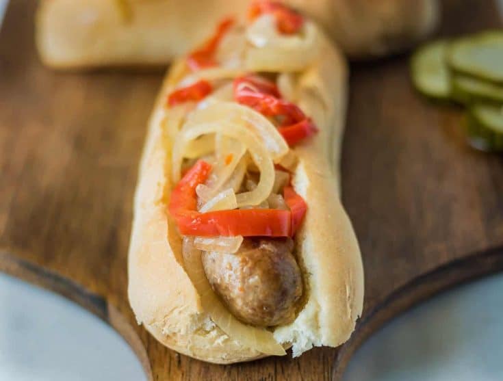 Slow cooker beer bratwurst on a bun with onions and peppers