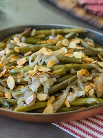 A copper serving dish filled with slow cooker green beans
