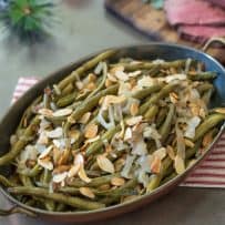 An oval serving dish of slow cooker green beans with shallots and almonds