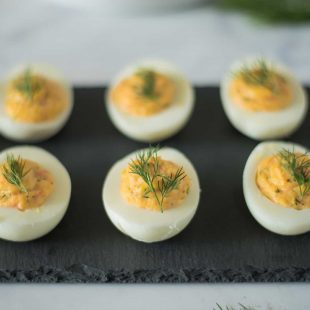 6 smoked salmon deviled eggs on a serving plate garnished with fresh dill