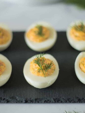 6 smoked salmon deviled eggs on a serving plate garnished with fresh dill