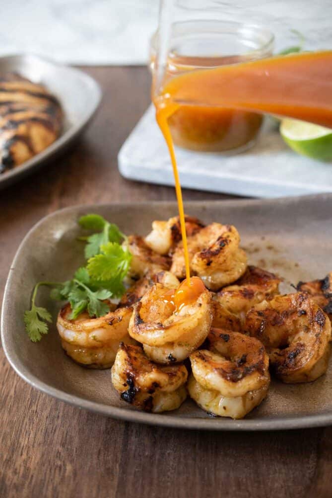 Pouring Sonoran Jalapeño Lime Sauce  over grilled shrimp