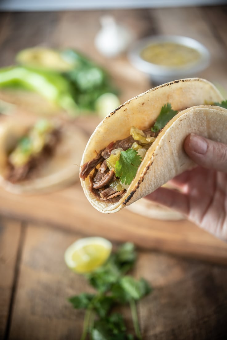 A closeup holding a taco with garnishes in background