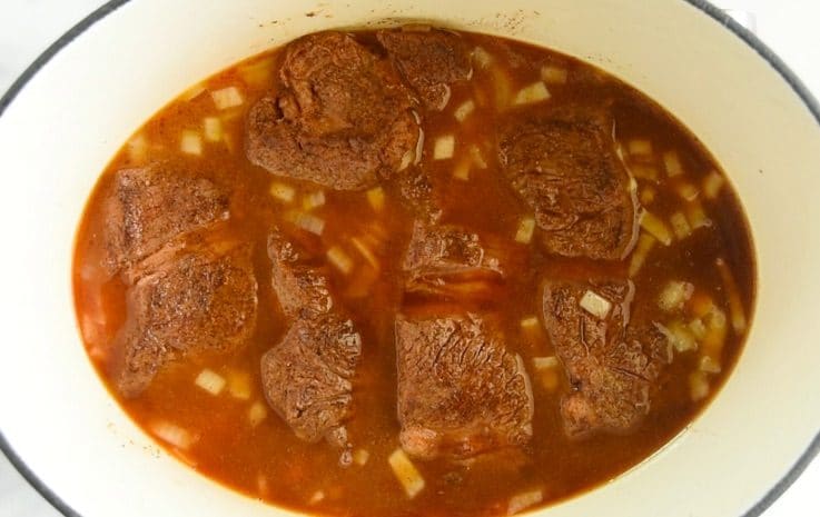 Beef chuck roast simmering in a beef sauce