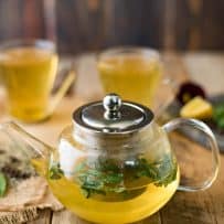 Fresh mint in a glass teapot of herbal tea with cups