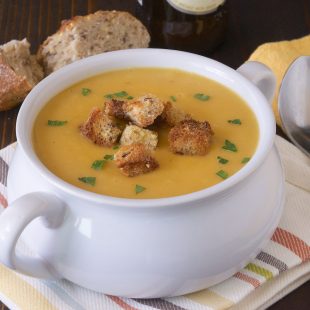 A spoon next to a white soup bowl of soup a la bier (beer soup)