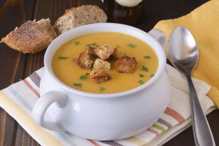 A spoon next to a white soup bowl of soup a la bier (beer soup)