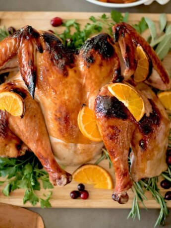 A spatchcock roasted turkey garnished with herbs and orange slices.