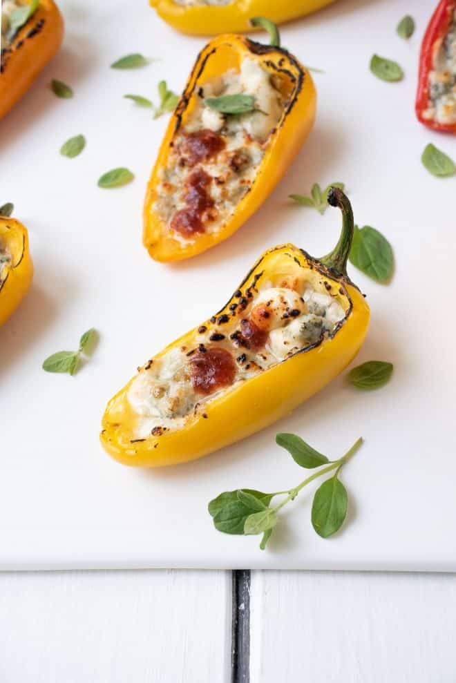 A closeup of a yellow mini sweet pepper filled with melted blue cheese and hot sauce