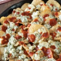Potato chips piled on top of each other topped with blue cheese and hot sauce