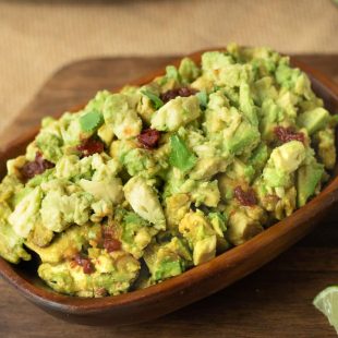 A wood bowl of spicy guacamole