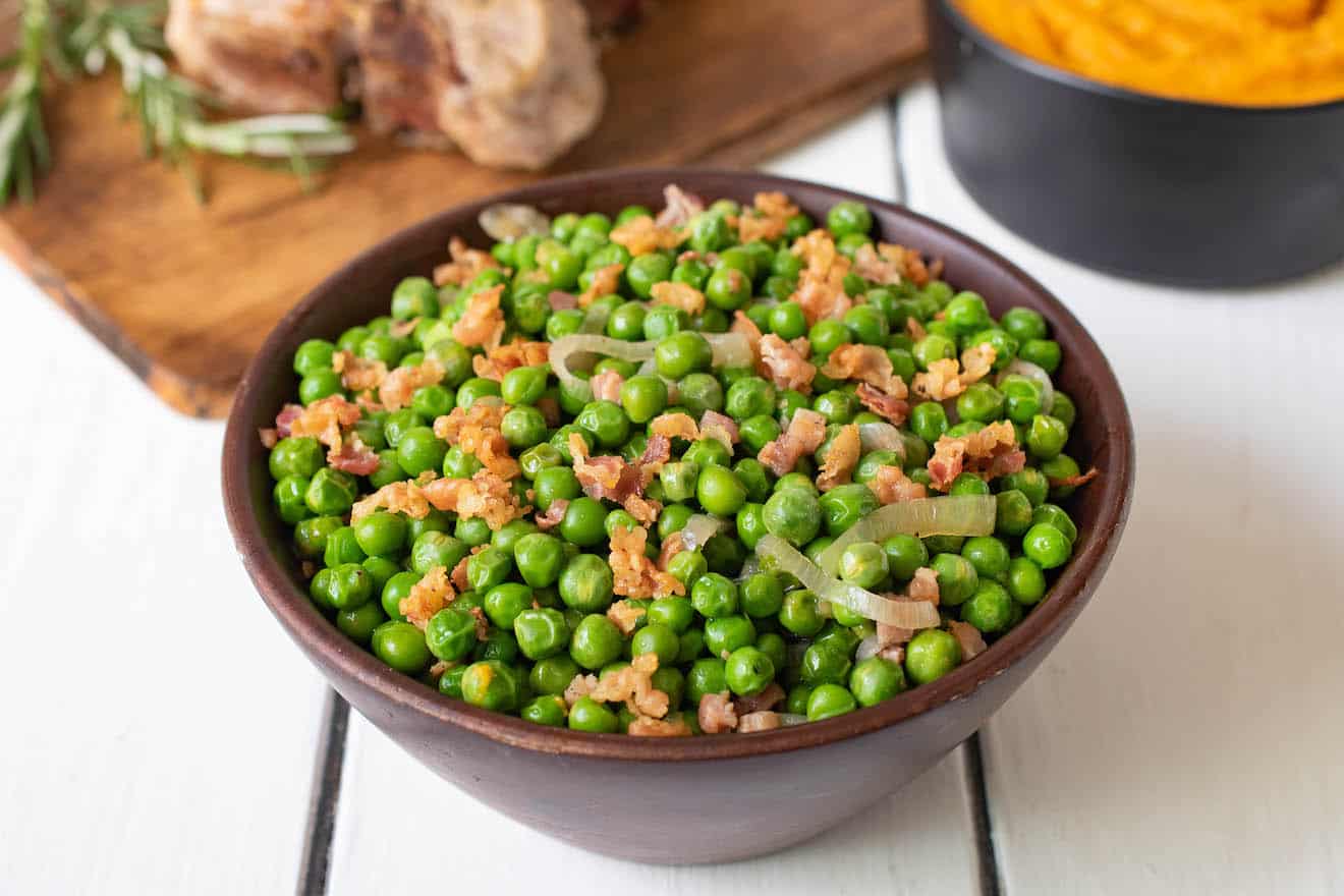 Crispy bits of pancetta and shallot in a bowl of green peas