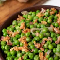 A closeup of green peas with pancetta and shallots