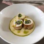 Sliced chicken roulade filled with vegetables served over polenta