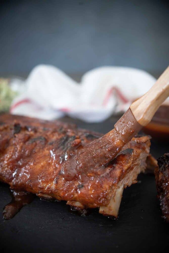 Brushing barbecue sauce over ribs