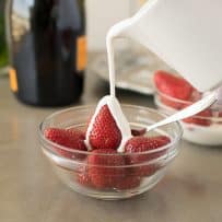 A perfect pour of cream over strawberries