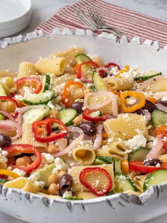 A bowl of pasta salad with vegetables and cheese.