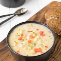 Summer corn chowder served in a black bowl with bread