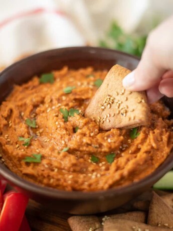 Using a pita chip to scoop up hummus