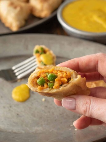A samosa cut open showing sweet potato and pea filling inside